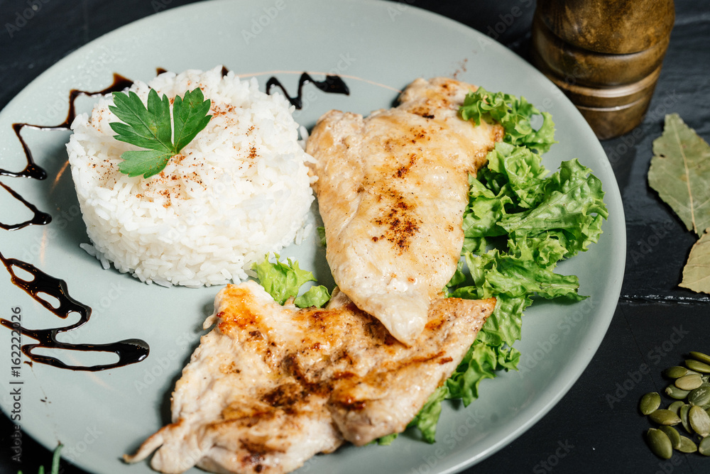 Close up details of grilled chicken breast with risotto and parsley