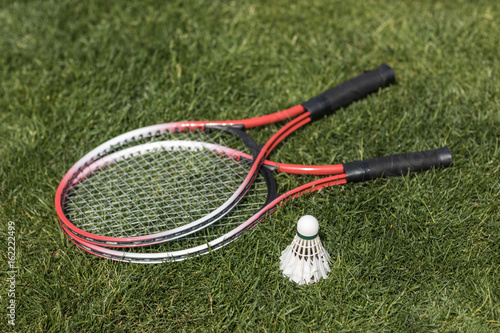 close up of badminton rackets with shuttlecock on grass