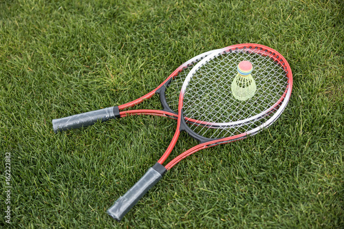 High angle view of two badminton racquets and shuttlecock on green grass