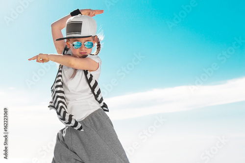 Fashion child dancing over sky background.