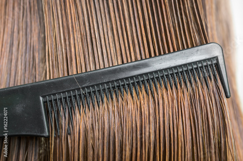 Close-up of dark wet hair with a comb - hair care concept photo