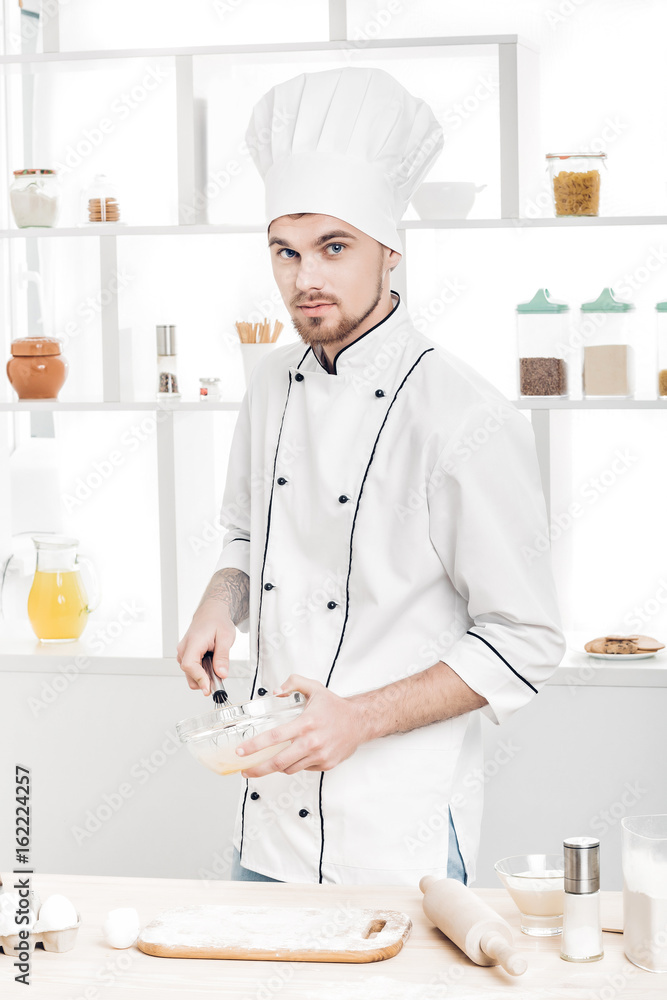 Chef in uniforms whipping eggs and milk in bowl in kitchen Chef in uniforms whipping eggs and milk in bowl in kitchen