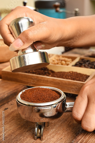 Freshly ground coffee beans in a metal filter on hand for background