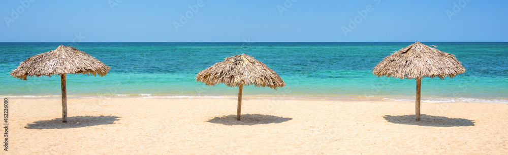 Straw umbrellas on a beautiful tropical beach, panoramic travel background, travel and tourism concept