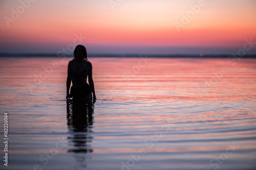 Woman silhouette in lake on sunset