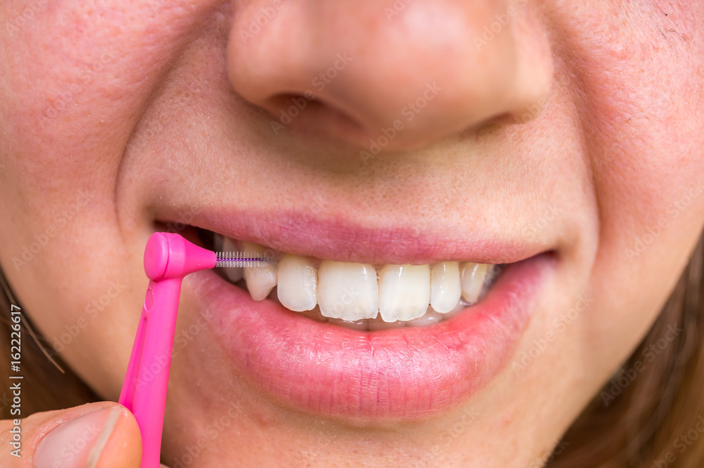 Naklejka premium Woman brushing her teeth with interdental brush