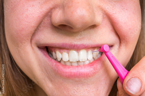 Woman brushing her teeth with interdental brush photo