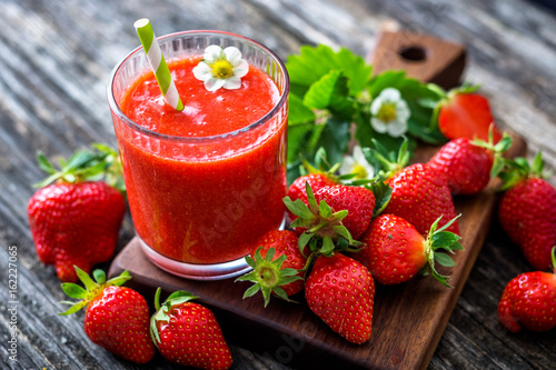 Strawberry smoothie and strawberries on wooden background