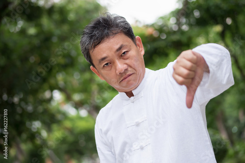 asian kung fu senior man showing thumb down hand gesture photo