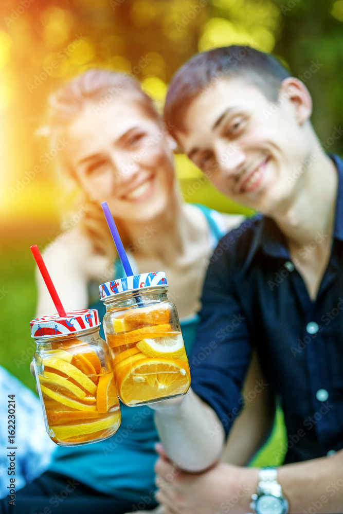 Lovers man and woman with detox water with orange and lemon. Summer Walk. The concept is healthy food, lifestyle and summer. Lovers man and woman with detox water with orange and lemon. Summer Walk. The concept is healthy food, lifestyle and summer.