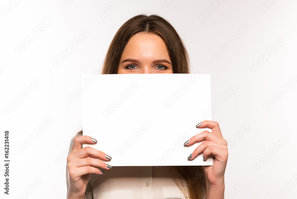 The girl is holding a sheet of blank paper in front of her The girl is holding a sheet of blank paper in front of her