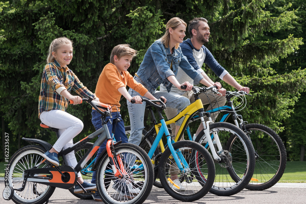 side view of happy family riding bicycles while spending time together in park side view of happy family riding bicycles while spending time together in park