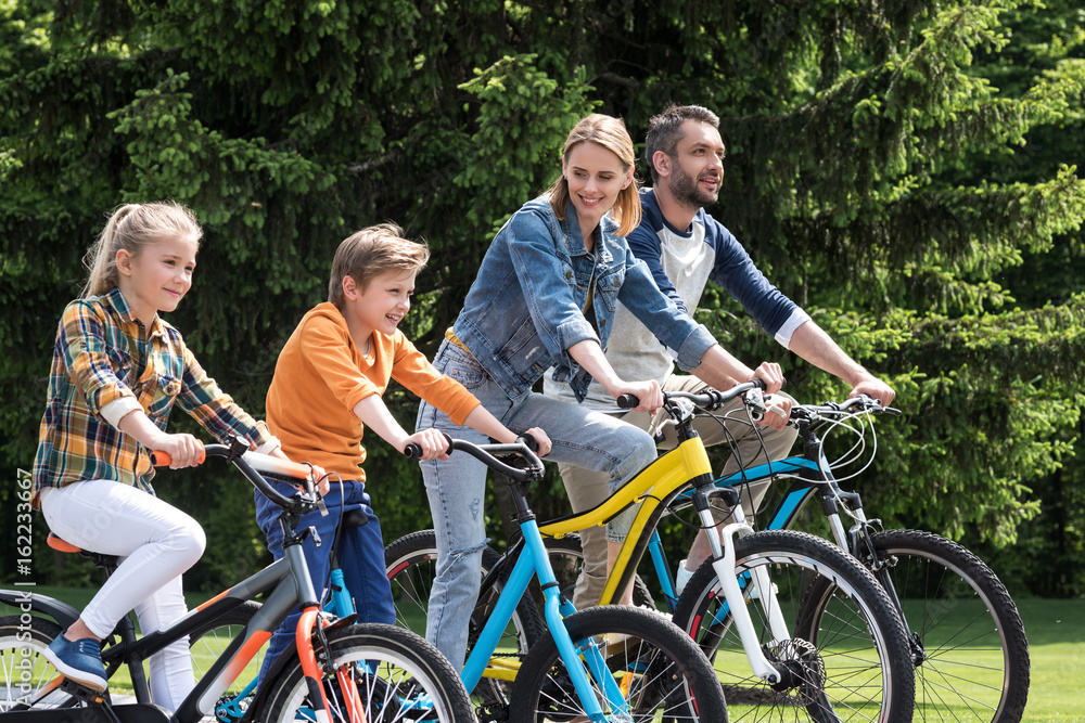 happy family riding bicycles while spending time together in summer park