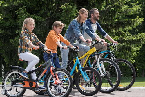side view of happy family riding bicycles while spending time together in park