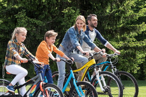 happy family riding bicycles while spending time together in summer park