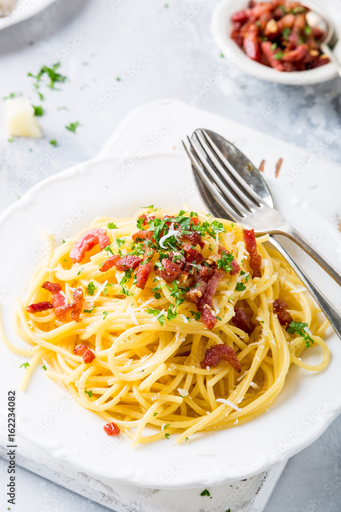 Italian pasta spaghetti Carbonara with fried bacon, parmesan cheese and parsley on white plate. Restaurant food concept.