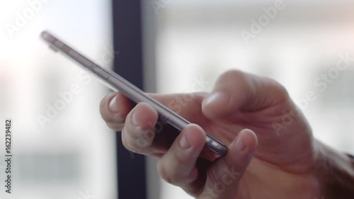 Businessman Texting on Smartphone  Businessman writing a sms message in an office. Shot on a Red Dragon in 4k down convert to HD.