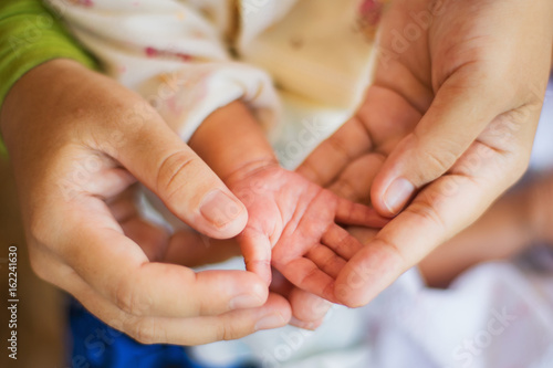 Female hand holding newborn baby's hand