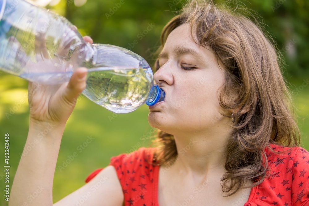 Young woman is drinking water from bottle at sunny hot day. Young woman is drinking water from bottle at sunny hot day.