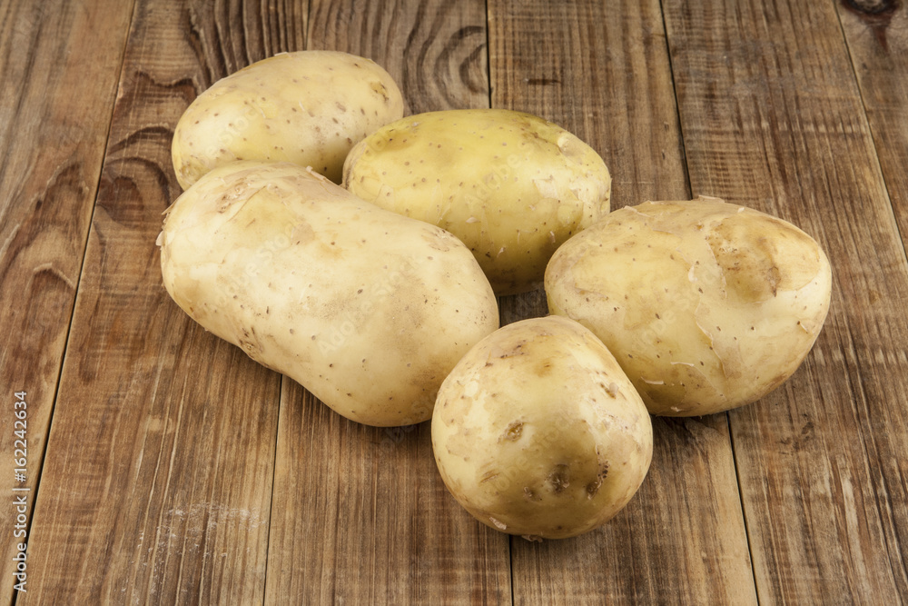 Raw, young potatoes on a wooden table Raw, young potatoes on a wooden table