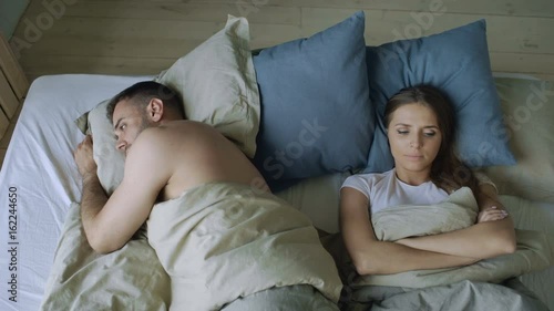 Top view of upset lying sleepless couple in bed offended because of quarrel