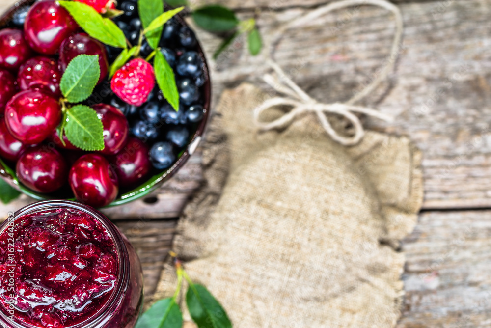 Homemade cherry jam and fresh cherries in a bowl on rustic background Homemade cherry jam and fresh cherries in a bowl on rustic background