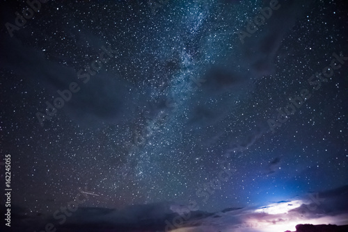 Night sky during thunderstorm in the distance with milky way and stars