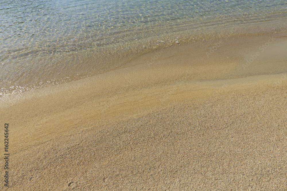 Soft sea wave on sandy beach, Beautiful Greek beach with fine sand, Close up photo of sandy beach with soft wave in motion Soft sea wave on sandy beach, Beautiful Greek beach with fine sand, Close up photo of sandy beach with soft wave in motion