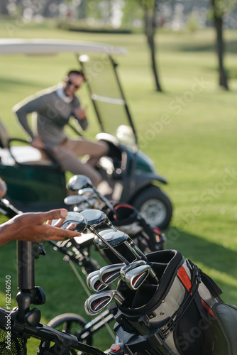 cropped view of golfer choosing golf club on golf course