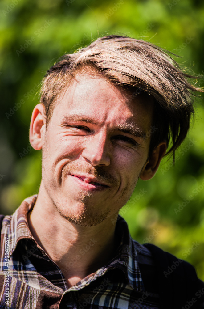 A young man with disheveled hair is smiling broadly A young man with disheveled hair is smiling broadly