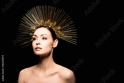 glamorous naked model posing in golden headpiece isolated on black
