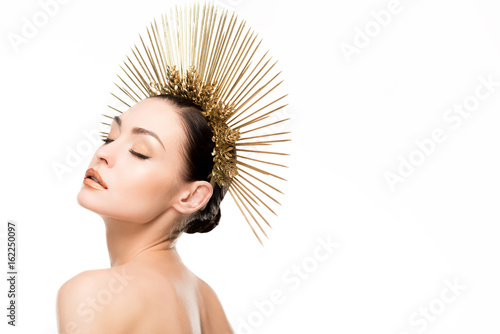 sensual naked woman with closed eyes wearing golden headpiece isolated on white