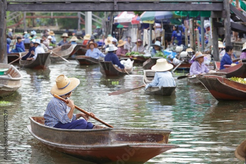 selective focus of trader taking boat in floating market for selling food and vegetable
