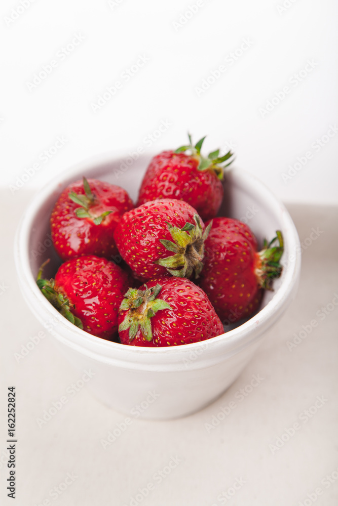 Strawberries in white bowl. Vertical composition with copy space. Summer natural beauty concept. Strawberries in white bowl. Vertical composition with copy space. Summer natural beauty concept.