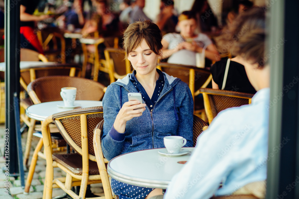 people, communication and dating concept - couple with smartphones drinking tea or coffee in strret table of cafe or restaurant