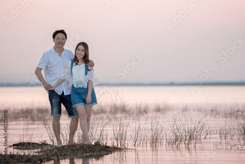 Beautiful young dating couple in city taking photos on park during sunset time