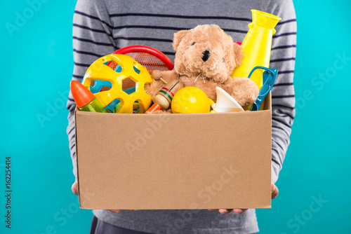 Male volunteer holding donation box with old toys. photo