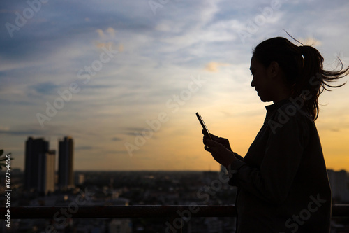 Silhouette of a woman use mobile phone in city background