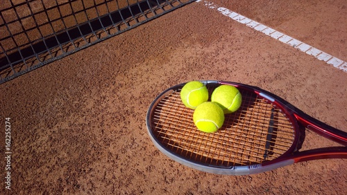 Tennisschläger mit Tennisbällen auf einem Tennisplatz © pattilabelle