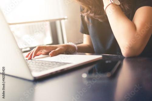 woman working on laptop,business office desk,using laptop computer technology on table for searching and planing successful concept,vintage tone and day light flare.