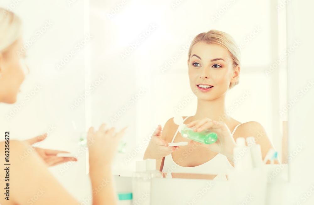 young woman with lotion washing face at bathroom young woman with lotion washing face at bathroom