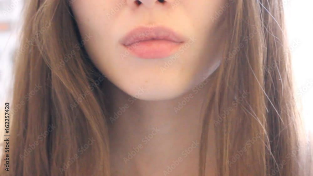Extreme close up of lips 18-year-old girl with smile. Without lipstick. Young attractive woman looking at camera and smiling. Beautiful white smile with even teeth. Long shiny hair Extreme close up of lips 18-year-old girl with smile. Without lipstick. Young attractive woman looking at camera and smiling. Beautiful white smile with even teeth. Long shiny hair