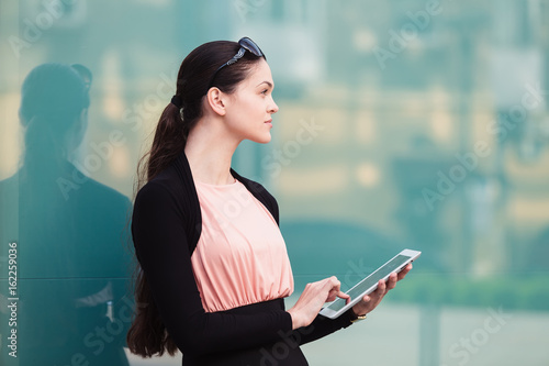 Business woman working with the tablet outdoors near the office