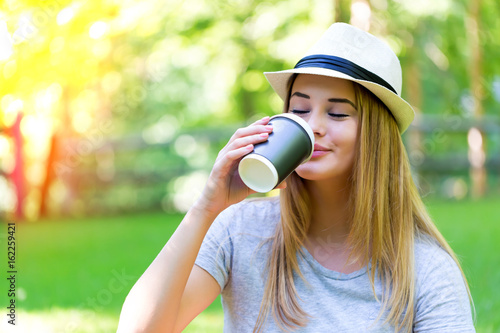 Young woman drinking coffee outside on a summer day