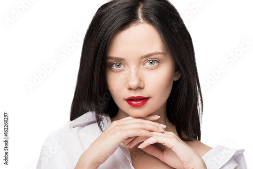 portrait of woman posing with hands on chin and looking at camera looking at camera isolated on white