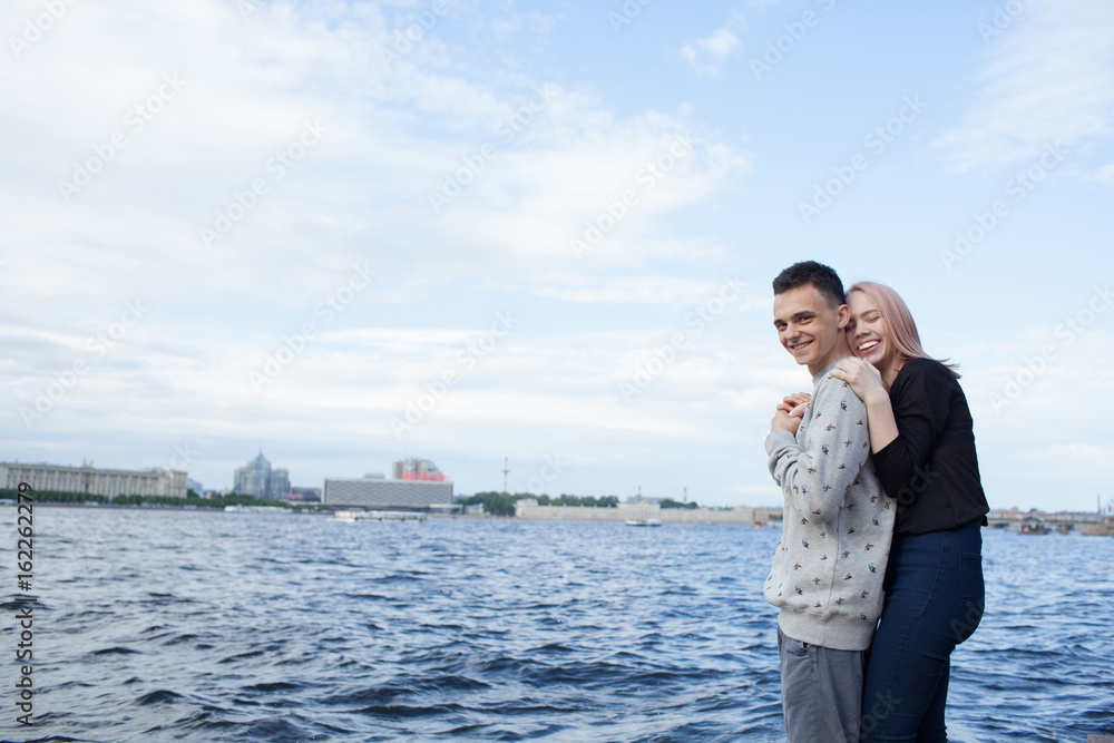 Young couple hugging and smiling on the background of the urban landscape. River embankment in Saint Petersburg Young couple hugging and smiling on the background of the urban landscape. River embankment in Saint Petersburg