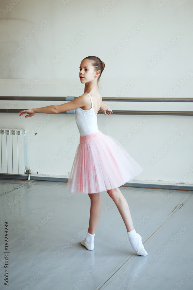 Cute little ballerina in pink ballet costume and pointe shoes is dancing in the room. Kid in dance class. Child girl is studying ballet. Copy space. Cute little ballerina in pink ballet costume and pointe shoes is dancing in the room. Kid in dance class. Child girl is studying ballet. Copy space.
