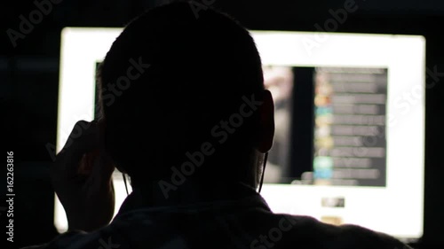 Young Man Back light Looks At Monitor