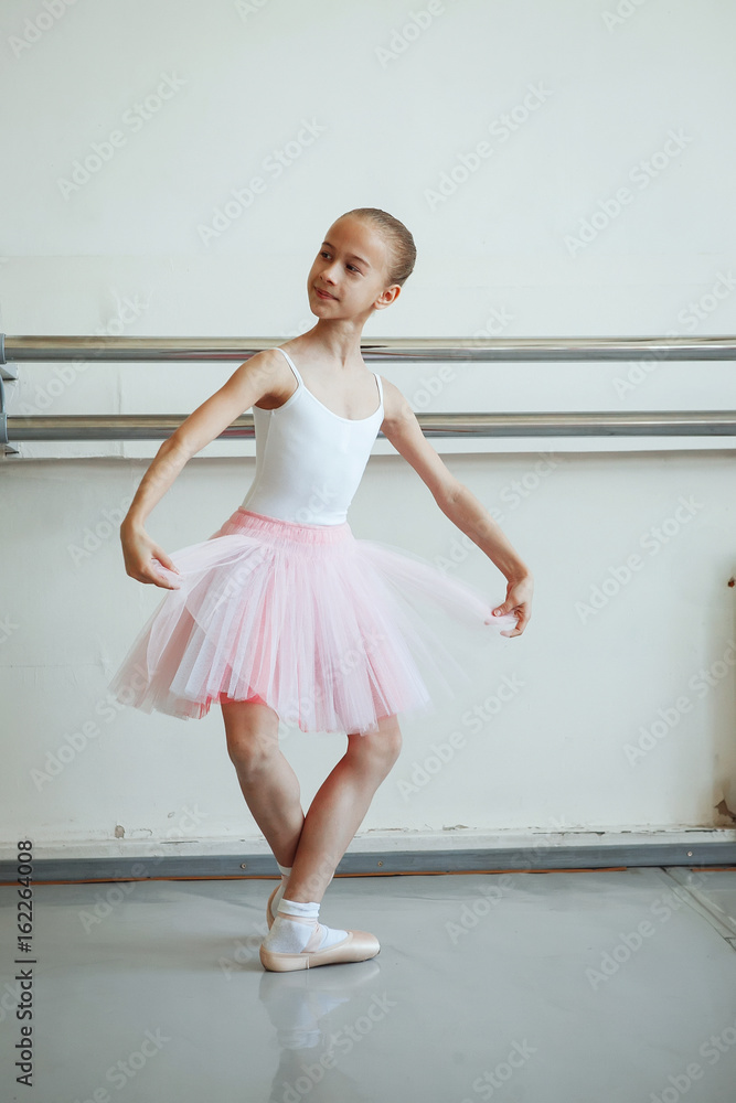 Cute little ballerina in pink ballet costume and pointe shoes is dancing in the room. Kid in dance class. Child girl is studying ballet. Copy space. Cute little ballerina in pink ballet costume and pointe shoes is dancing in the room. Kid in dance class. Child girl is studying ballet. Copy space.