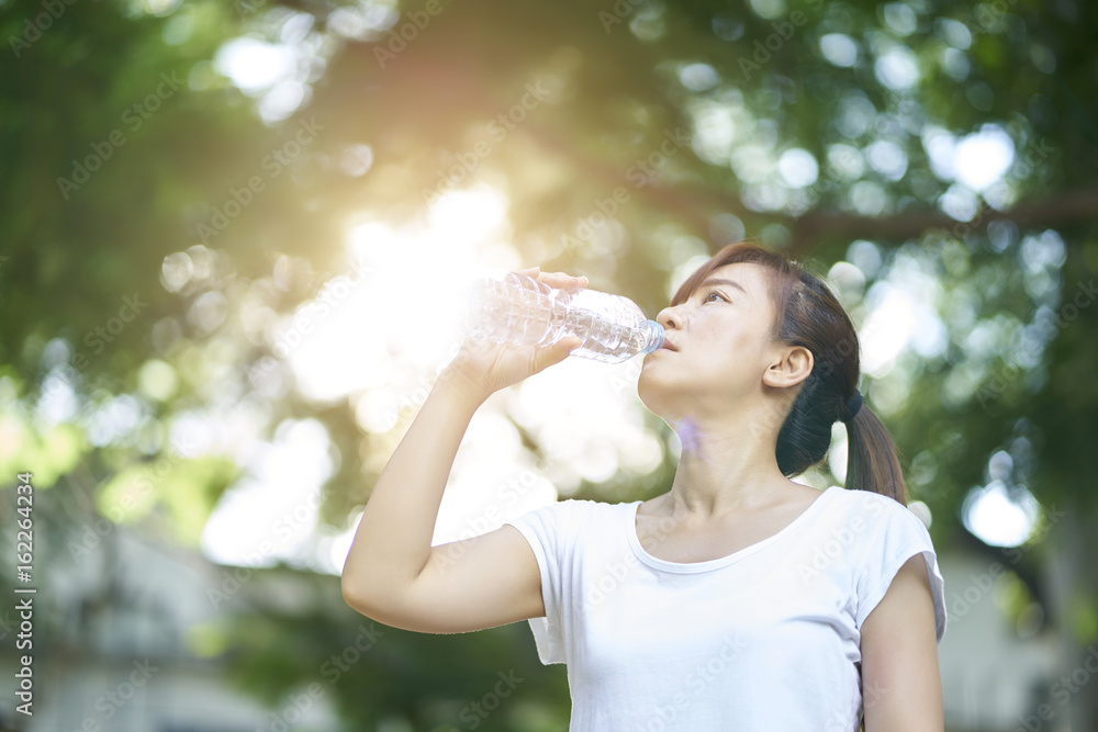Sporty girl drink water after running in park Sporty girl drink water after running in park